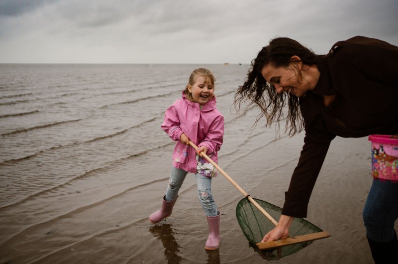 Op-deze-foto-staat-een-vrouw-met-kind-en-een-schepnet-op-het-strand-van-Rockanje