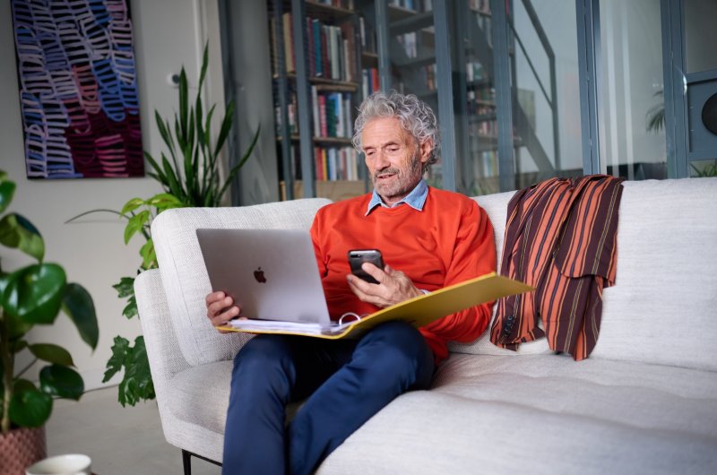 Vitale senior achter zijn laptop, bellend met hypotheekadviseur van Rabobank.