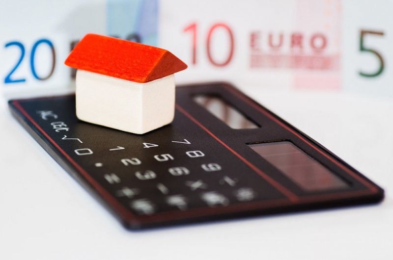 Rekenmachine met mini-huisje en eurobiljetten